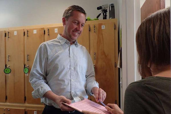 Man providing test forms to student